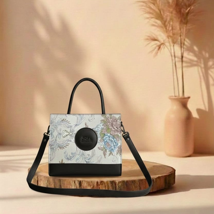 blackHandbag with floral design on a wooden stand against a beige background