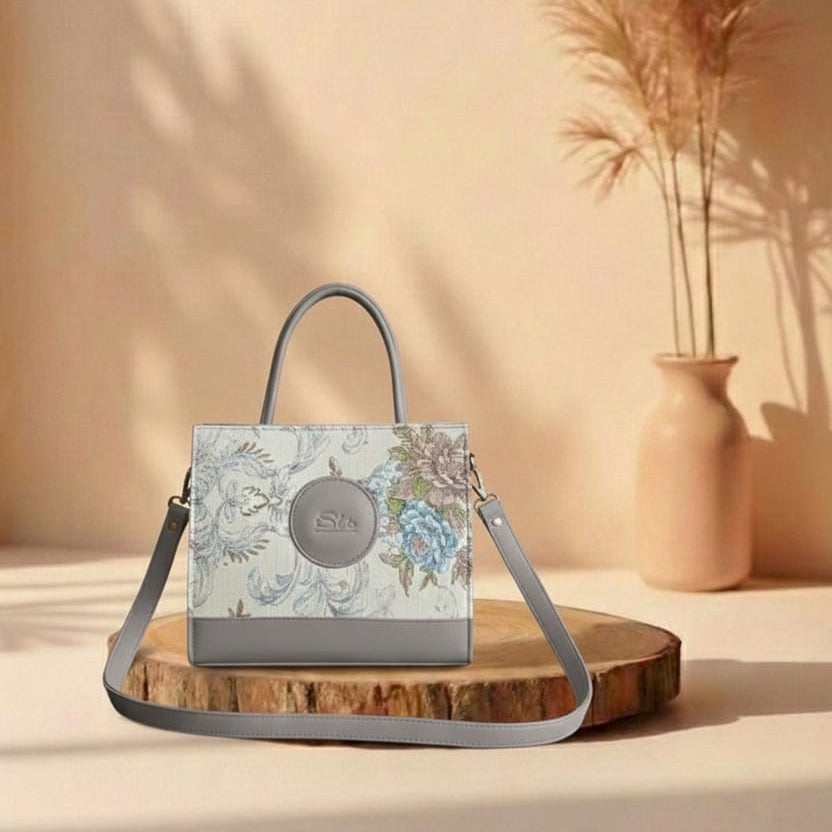 grey Floral handbag on a wooden stand with a vase and plants in the background