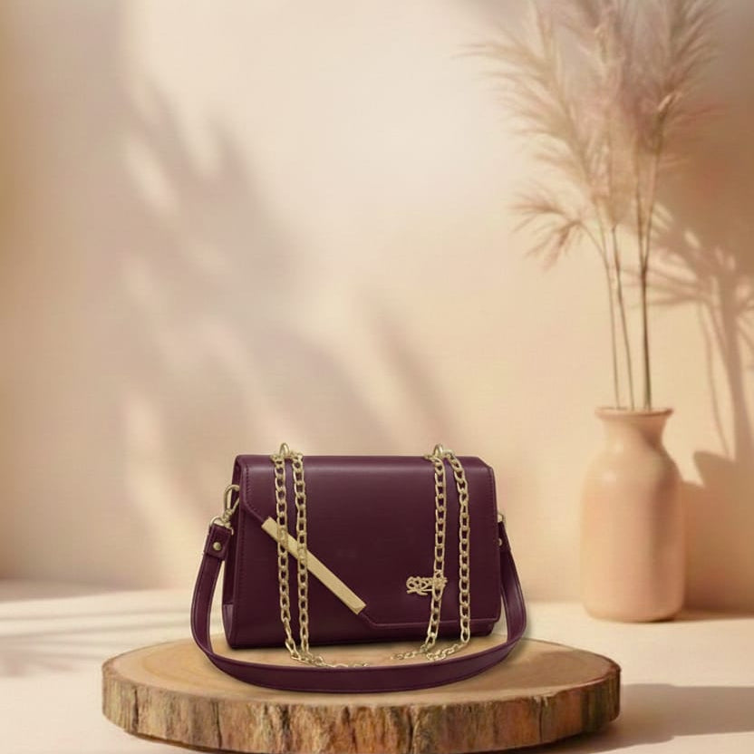 burgundy handbag with gold chain on a wooden stand against a beige background